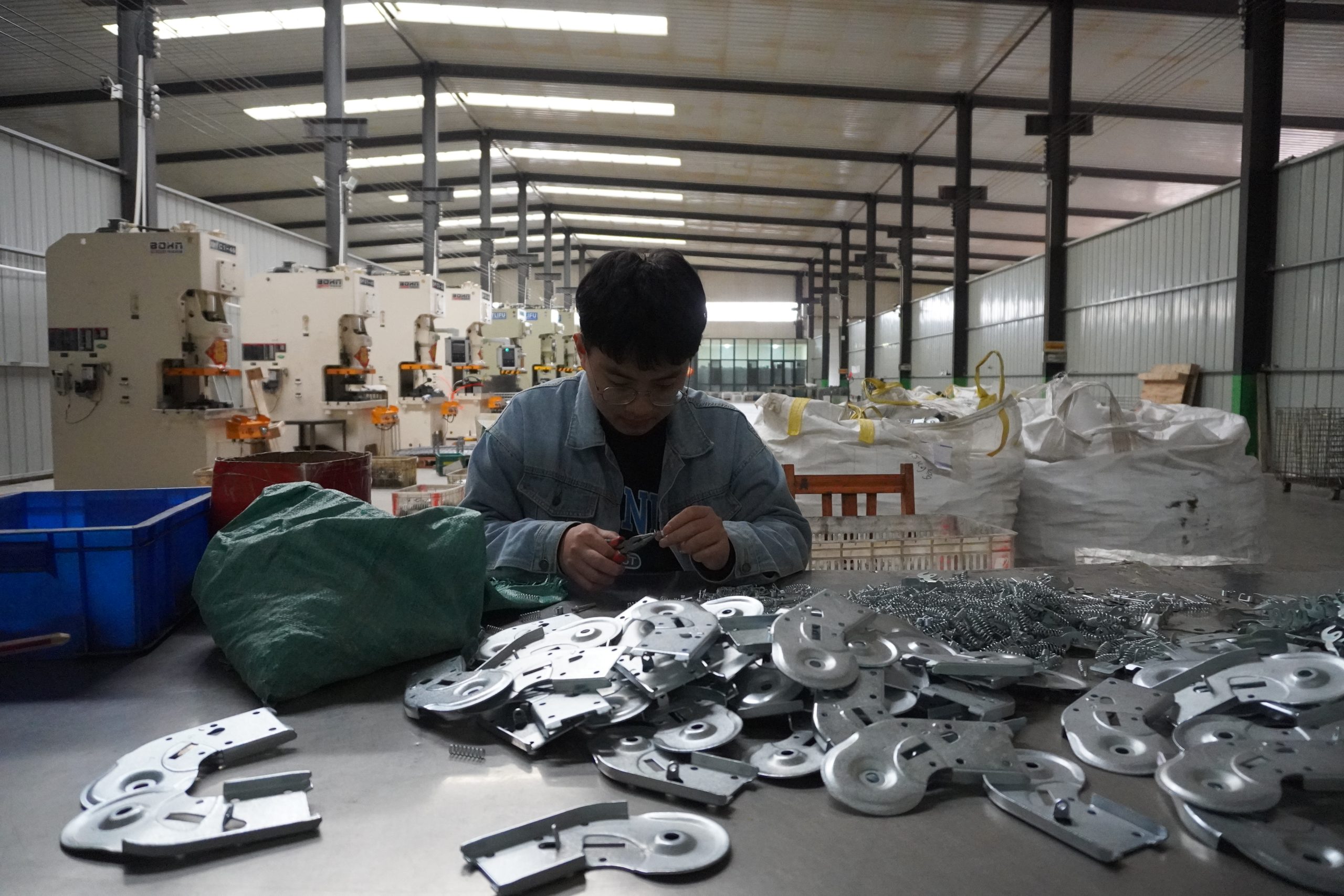 Worker inspecting polished metal parts at a workbench